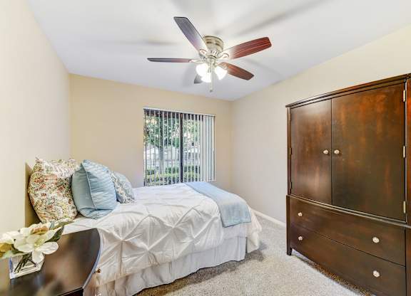 A bedroom with a bed, dresser, and ceiling fan.