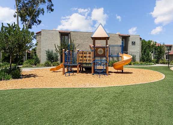 A playground with a yellow slide and a brown and blue play structure.