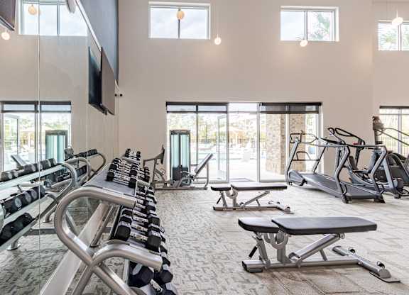 A gym with a variety of equipment including treadmills, weights, and exercise machines.