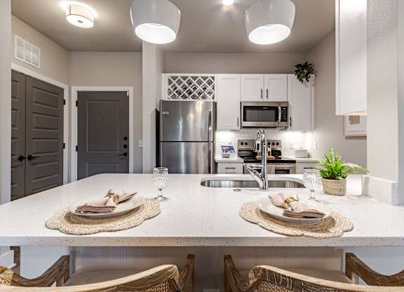 A modern kitchen with a dining table set for two.