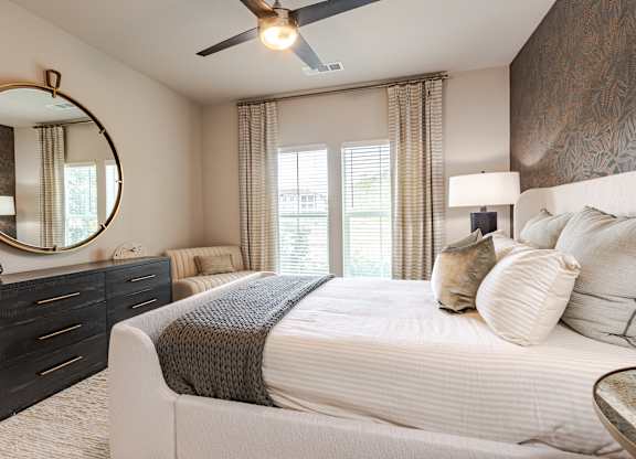 A bedroom with a large bed, a dresser, and a ceiling fan.