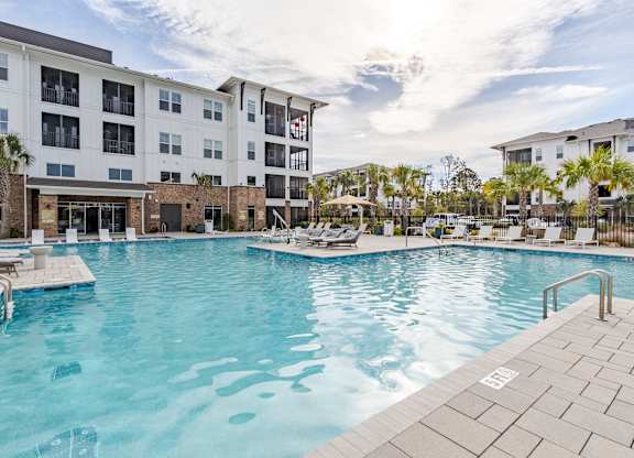 A large swimming pool in front of a multi-story apartment building.