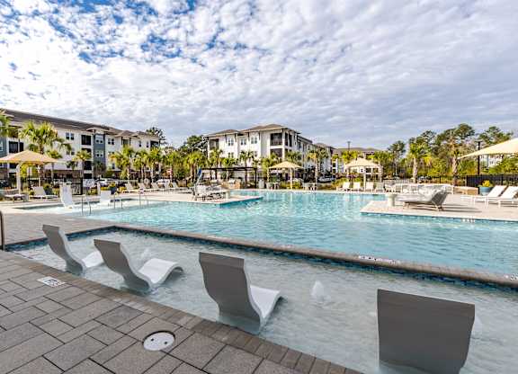 A pool with chairs around it and a building in the background.