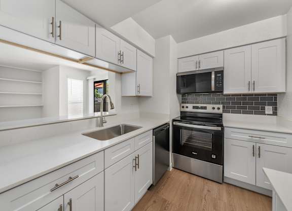 A modern kitchen with white cabinets and stainless steel appliances.