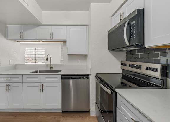 A kitchen with white cabinets and a black microwave.
