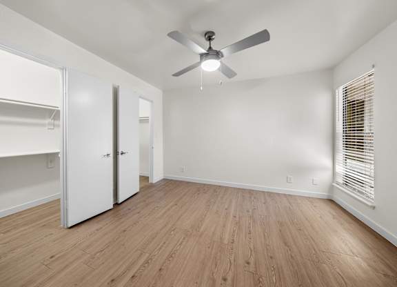 A room with a ceiling fan and wooden flooring.