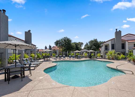 A large outdoor swimming pool surrounded by lounge chairs and umbrellas.