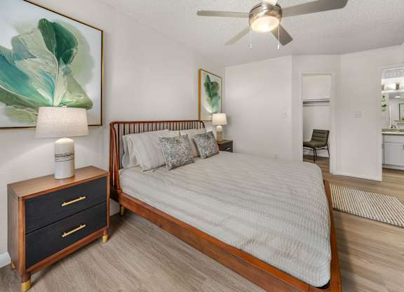 A bedroom with a bed, nightstand, and a painting on the wall.
