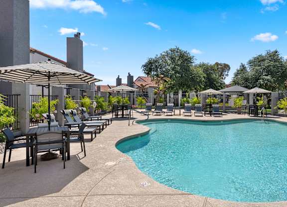 A large outdoor swimming pool surrounded by lounge chairs and umbrellas.