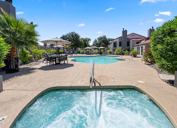 A hot tub in the middle of a pool surrounded by a house and trees.
