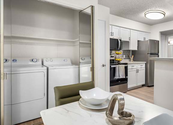 A modern kitchen with white appliances and a marble table.