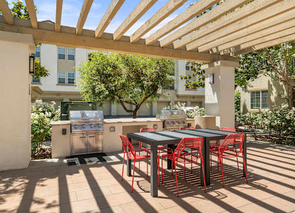 A patio with a table and chairs under a wooden pergola.