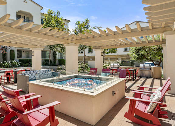 A pool surrounded by red chairs and a white pergola.