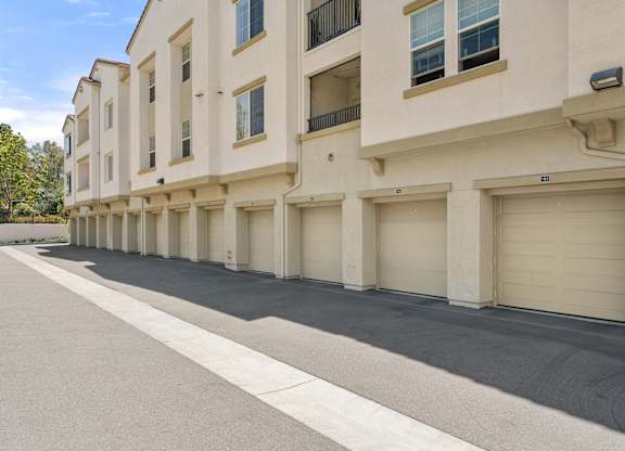 A row of beige townhouses with garages on the side.