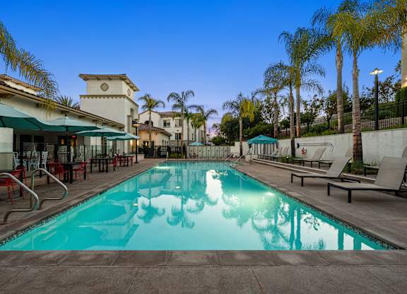A swimming pool surrounded by palm trees and lounge chairs.