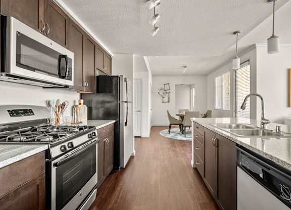 A modern kitchen with dark wood cabinets and stainless steel appliances.