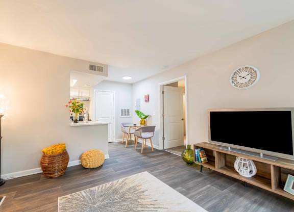 A living room with a television, a chair, a table, and a clock on the wall.