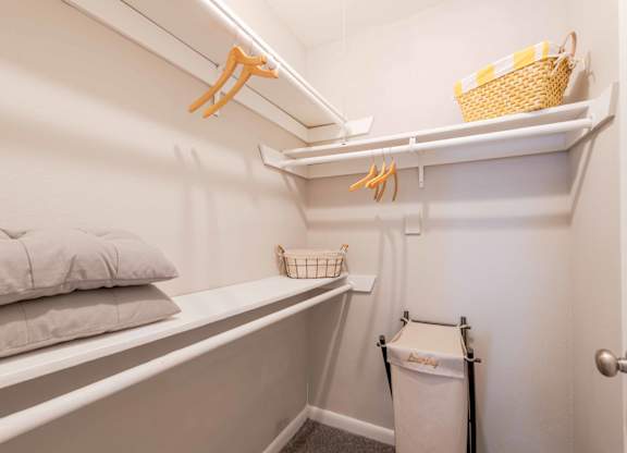 A small white closet with a basket on top shelf.
