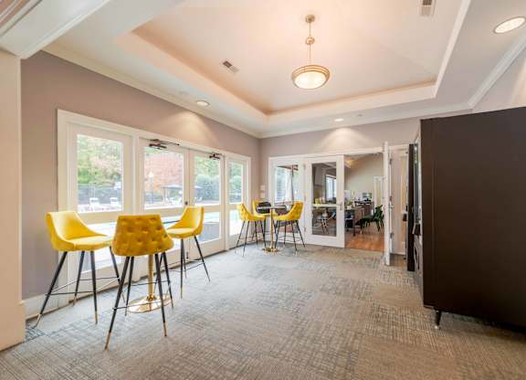a room with high top tables with yellow chairs