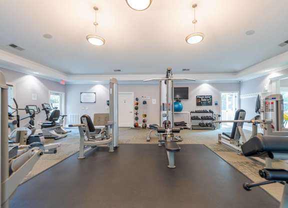 A spacious gym with various exercise equipment and a large mirror on the wall.