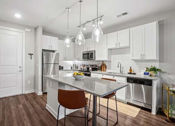 A modern kitchen with a center island and pendant lights.
