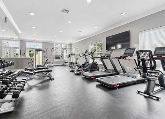 A spacious gym with a variety of equipment including treadmills, stationary bikes, and weight machines.
