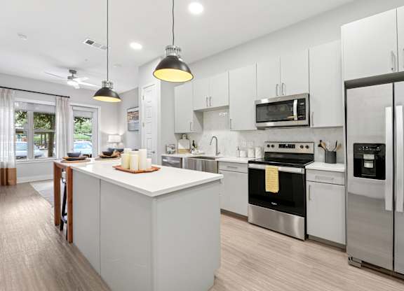 A modern kitchen with a white island and stainless steel appliances. at Trailhead, Austin, Texas