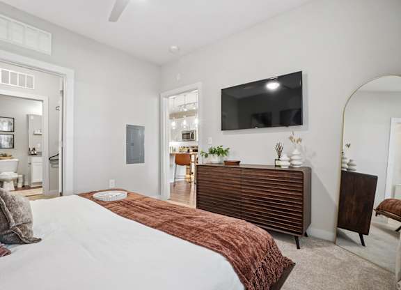 A bedroom with a large bed and a flat screen TV mounted on the wall.
