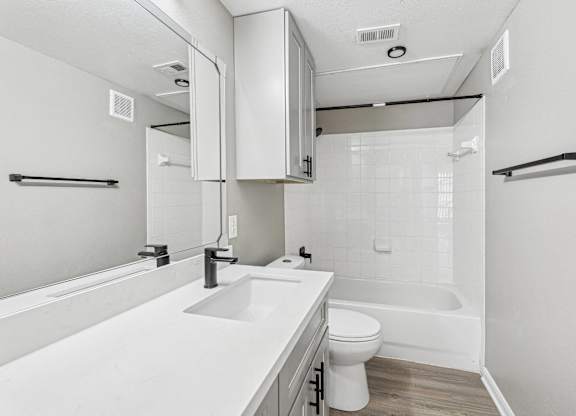 A white bathroom with a toilet, sink, and bathtub at Clear Creek Meadows Apartments, Texas