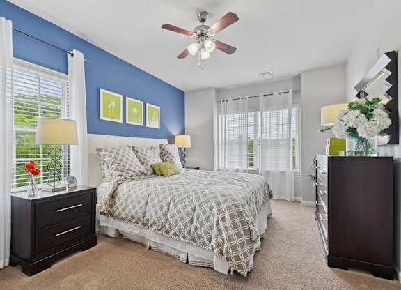 A bedroom with a bed, nightstand, and a ceiling fan.