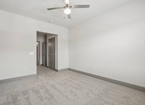 A room with a ceiling fan and a carpeted floor.