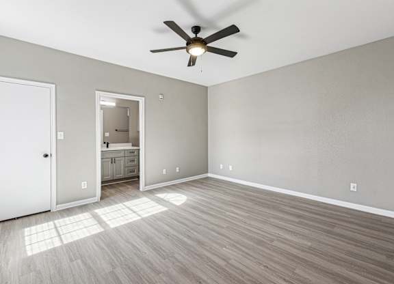 A room with a ceiling fan and light, hardwood floors, and a white door at Clear Creek Meadows Apartments, Copperas Cove, TX, 76522