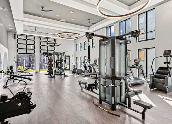 A gym with a variety of equipment including treadmills, weights, and exercise machines.