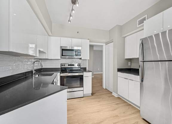 a modern kitchen with stainless steel appliances and white cabinets