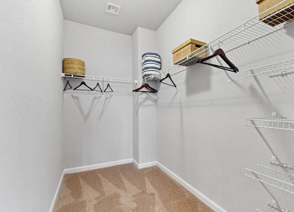 A walk in closet with clothes hanging on racks and shelves.