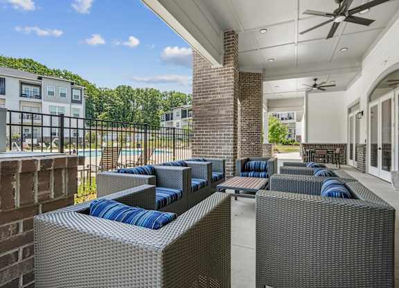 A patio with grey wicker furniture and a brick pillar.