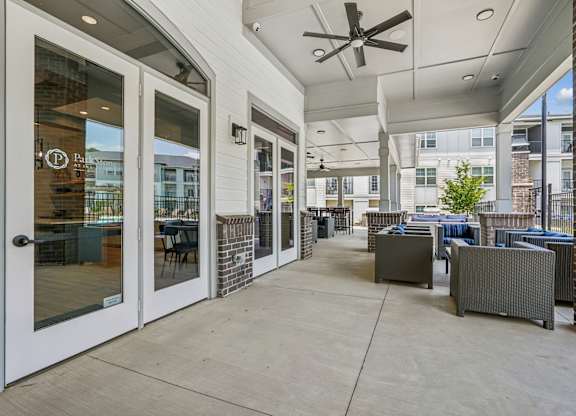 A patio area with a table and chairs and a ceiling fan.
