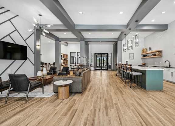 A modern living room with a wooden floor and a kitchen area in the background.