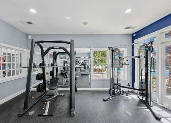 A gym with a variety of equipment including a squat rack, a leg press machine, and a bench press.