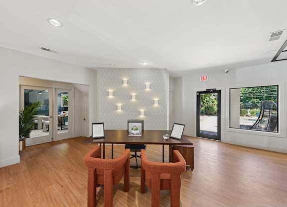 A room with a table and chairs in the center with a wall of windows on the right.