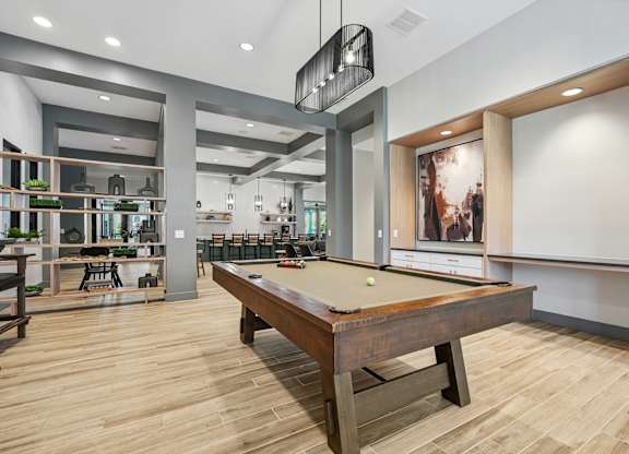 A pool table is in the middle of a room with a bar and a dining area.