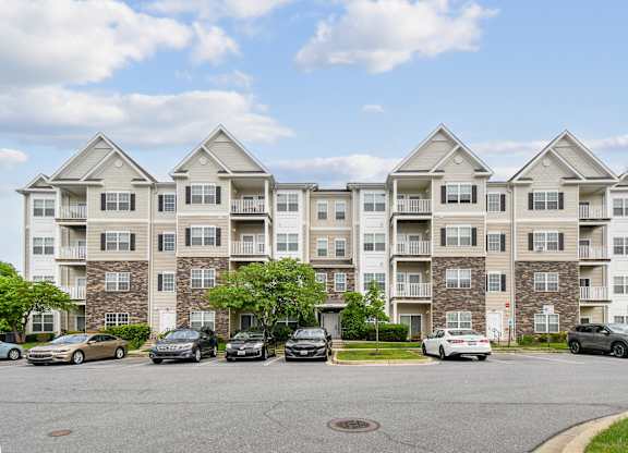 A large apartment building with cars parked in front.