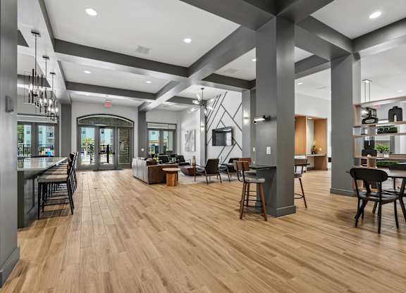 A modern open plan kitchen, dining and living room with wood flooring and dark grey columns.
