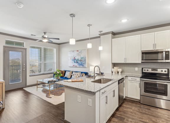 a kitchen with an island and a living room with a door to a balcony