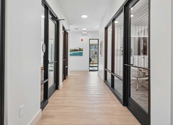 A long hallway with black doors and wood floors.
