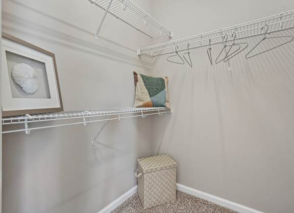 A room with a white wall and a white shelf with a picture frame and a green pillow on it.