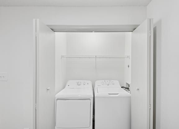 Two white front loading washing machines in a small laundry room.