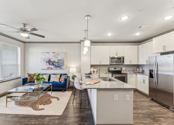 a kitchen and living room with stainless steel appliances and a granite counter top
