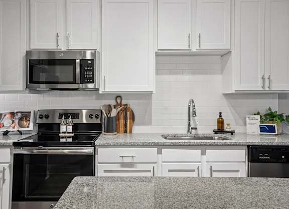 A modern kitchen with white cabinets and a granite countertop.