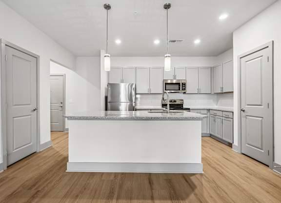 A modern kitchen with a white island and wooden floors.